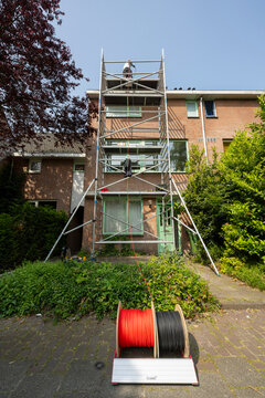 Engineer using cable spools to install solar panels on roof of house under sky