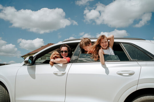 Happy family with Maltipoo dog in white car on sunny day