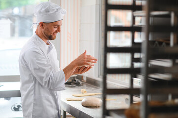 happy baker kneading dough at baking manufacture