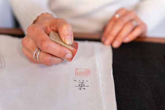Hand of woman using Japanese stamp on paper