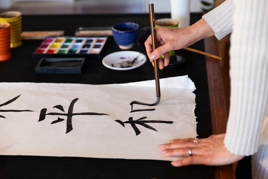 Hand of artist drawing in shodo on washi paper at home