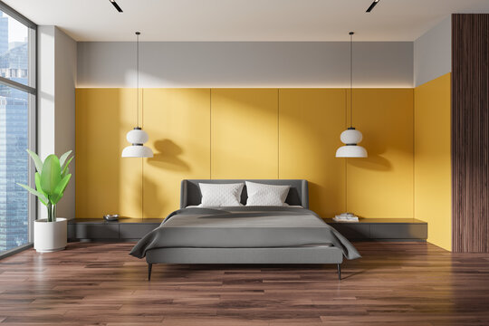 Modern bedroom with a gray bed, yellow accent wall, large windows, light wooden floor, and green plant, concept of urban living.  3D Rendering
