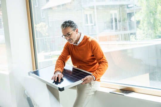 Mature businessman examining solar panel in office