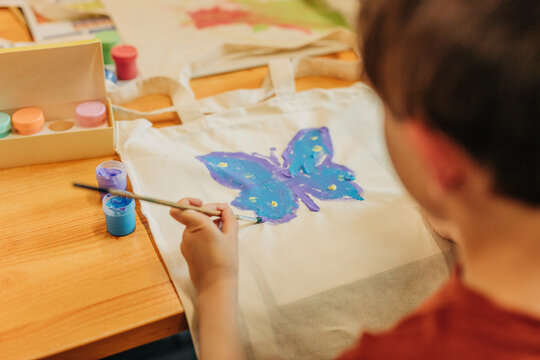 Boy shading butterfly with paintbrush at home