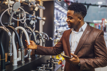 Portrait of buyer in bathroom store. Man is choosing faucet for his apartment.