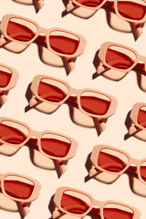 Minimal pattern of Stylish sunglasses with pink Frame on peach beige color background, sunlight shadow, summer fashion plastic-framed glasses. Aesthetic top view eyewear, geometric patterns