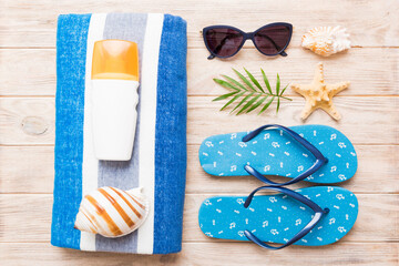 Summer holiday concept. Top view of beach towel, flip flop and sunscreen cream on table Top view...