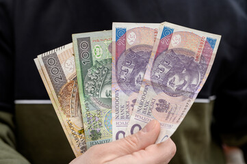 Mężczyzna trzyma banknoty w ręce, oszczędności, płaca minimalna