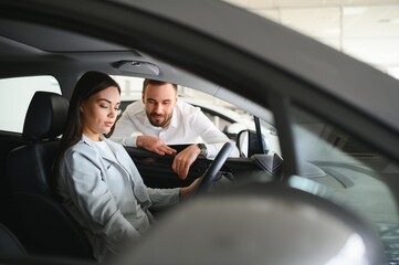 Beautiful young female client customer choosing new car