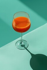 Orange juice in a glass on a turquoise background with shadow