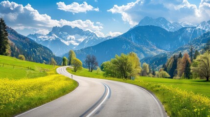 Fototapeta premium Panorama of picturesque mountain scenery in the Alps with fresh blooming green fields cutting the road on a sunny spring day, Germany