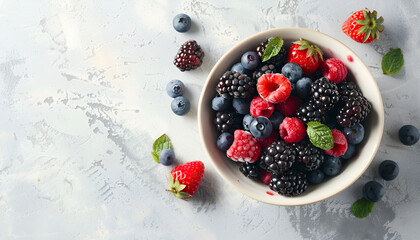 Different fresh ripe berries in bowl on light grey table, top view