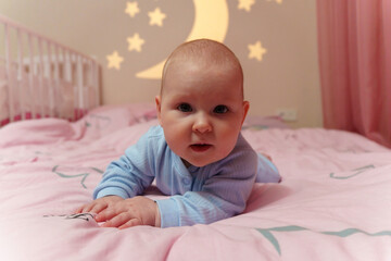 Baby is laying comfortably on top of a soft pink bed, looking content and cozy in the serene setting.