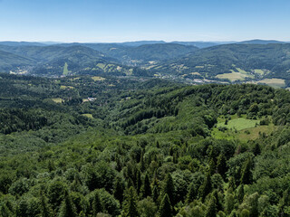 Obraz premium Drone fly above green mountains in summer. Polish green mountains and hills aerial drone photo. Drone view in Beskid mountains, Blatnia. Summer green forest on Blatnia. Beskid mountains in Jaworze.