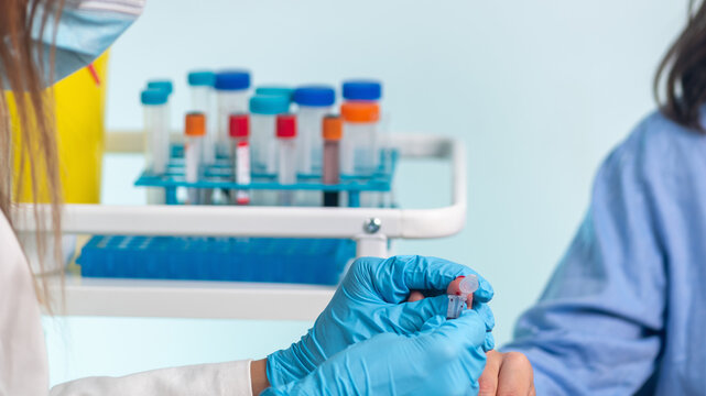 Nurse performs finger prick blood draw on patient for sample collection.