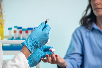 Nurse performs finger prick blood draw on patient for sample collection.