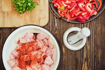 Top view of kitchen table with copped chicken fillet, bell pepper and cilantro