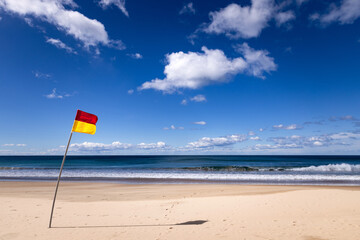 Australian surf life saving flag blowing in the breeze on a sandy Australian beach with vibrant...
