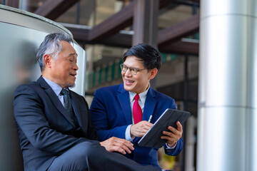 Professional Asian businessman and senior executive working and discussion business economy financial outside office building. Business people startup teamwork meeting corporate business in the city.