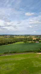 The lush green countryside fields stretch under a peaceful blue sky, creating a tranquil and picturesque landscape