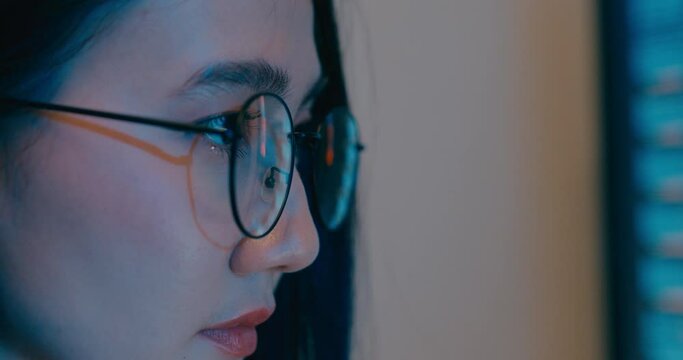 Closeup young Asia female freelance eyeglasses typing write prompt AI bot IT program nomad, video game, terminal with coding language, designer, big data center on desktop computer in night office.