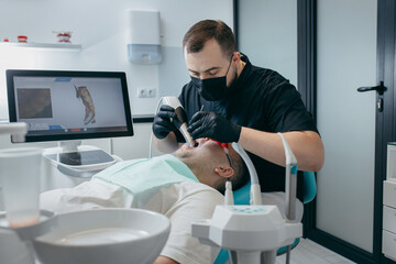 Dentist scanning teeth of male patient with modern scanning 3d machine