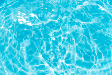 Blue water with ripples on the surface. Defocus blurred transparent blue colored clear calm water surface texture with splashes and bubbles. Water waves with shining pattern texture background.