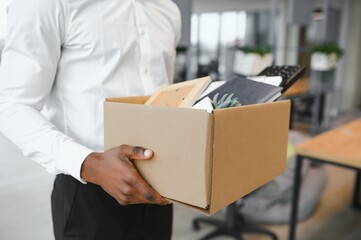 Young african man fired holding box with personal items at business office