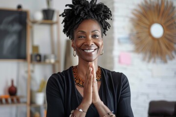 Portrait of a smiling afro-american woman in her 40s joining palms in a gesture of gratitude isolated in stylized simple home office background