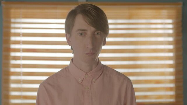 Quirky Man Stood by a Window Reacting Confused, Static Mid Close Up