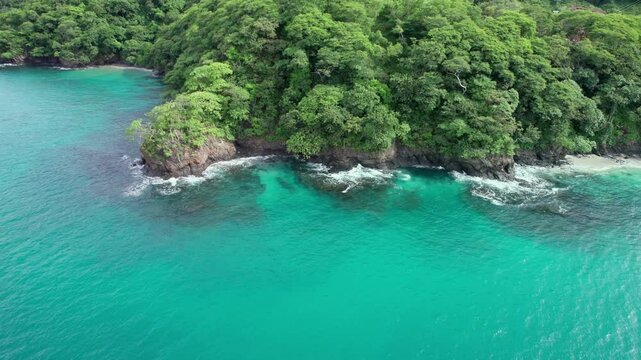 Aerial Flyover Turquoise Blue Ocean With Green Trees On Cliffs, Penca Beach, Costa Rica 4K Drone
