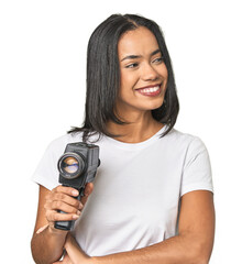 Latina with vintage camera, filming smiling confident with crossed arms.