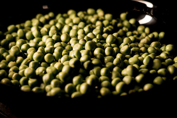 Green peas in a plate on a black background