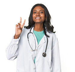 Young Indian doctor with stethoscope showing victory sign and smiling broadly.