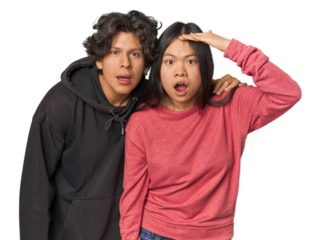 Young interracial couple in studio shouts loud, keeps eyes opened and hands tense.