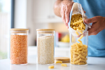 Close Up Of Man Filling Up Storage Jar From Bag In Kitchen At Home
