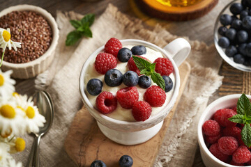 A cup of cottage cheese blended with flax seed oil with fresh raspberries and blueberries on a table