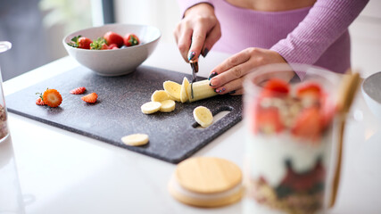 Close Up Of Woman In Fitness Clothing At Home In Kitchen Mixing Ingredients For Healthy Breakfast