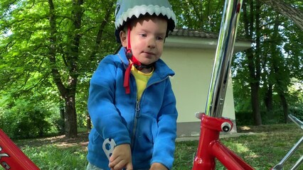 child little boy with wrench playing unscrewing nuts on bicycle in summer park