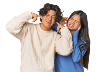 Young interracial couple in studio covering ears with fingers, stressed and desperate by a loudly ambient.