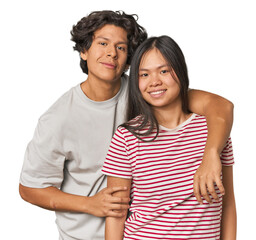 Happy multiracial couple hugging and looking at camera in studio