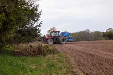 Obraz premium the tractor is doing autumn field work on the field