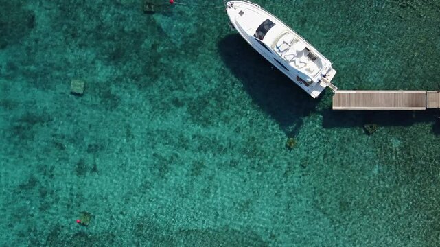 One White Yacht Moored at Wooden Jetty in Blue Clear Beach Water, Drone Top Down