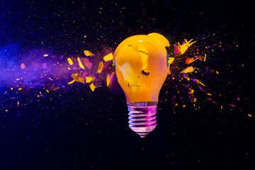 Yellow light bulb exploding black background