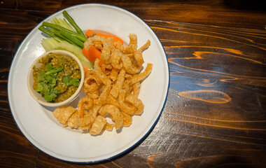 Nam Prik Num (Northern Thai Green Chilli Dip) and Pork Cracklings on a White Plate.