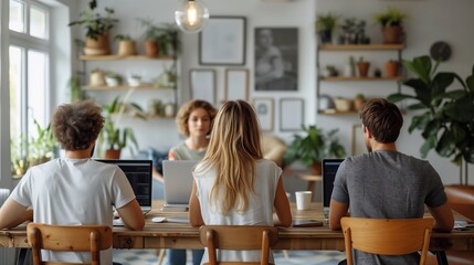 Fototapeta premium Team Working Together in Modern Office. Team of young professionals working together on laptops in a modern office with natural light and greenery, fostering a collaborative environment.