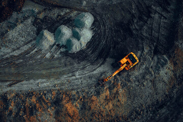 Excavator at work on a dark background. Top view from a drone