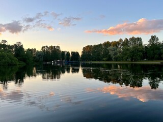 purple clouds reflection on the lake surface, trees silhouettes reflections on the water surface, twilights lake in the park, natural colors, very calm and peaceful