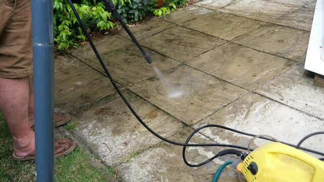 Cleaning terrace with high-pressure water blaster, cleaning dirty paving stones