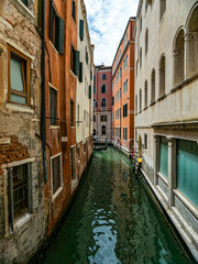 Vintage, colorful buildings on a narrow Venetian channel. Travel to Venice, Italy.